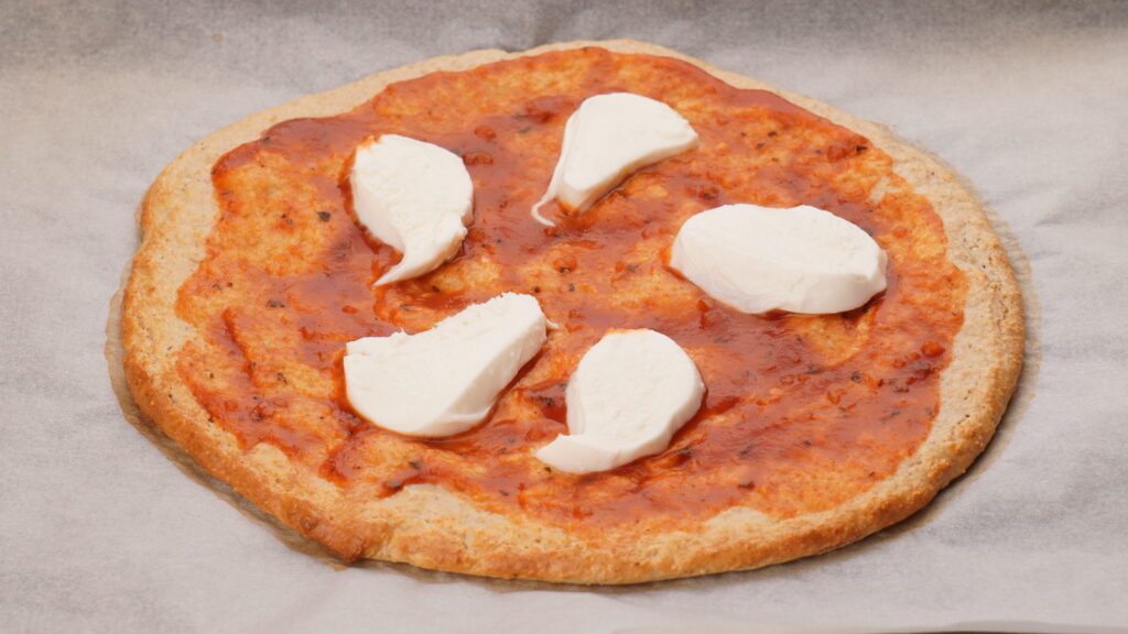 ピザソースとモッツァレラチーズをのせたピザ生地