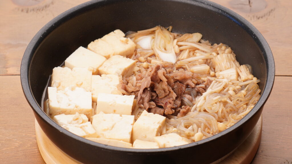 炒めた牛肉の周りに豆腐、白ねぎ、えのきを並べて調味料をかけたもの